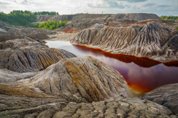 Fiume inquinato con del gasolio che assume una agghicciante colorazione rosso e ocra